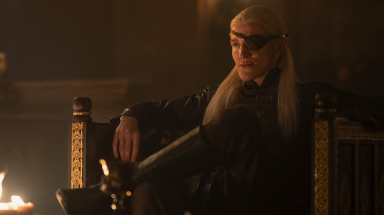 Aemond Targaryen sitting by fire