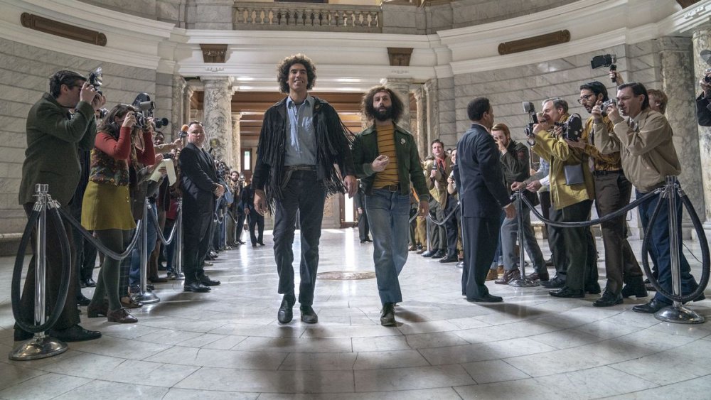 Sacha Baron Cohen as Abbie Hoffman walks confidently into the courtroom in The Trial of the Chicago 7