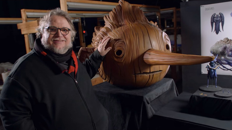 Guillermo del Toro standing with giant Pinocchio puppet head