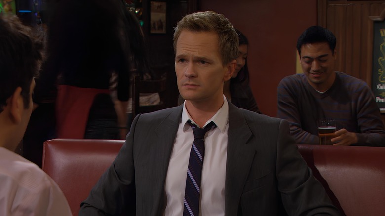 Barney sitting in booth looking at someone 