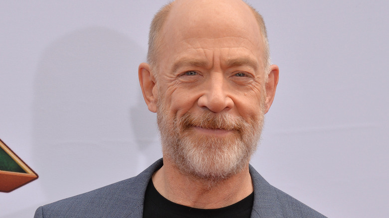 J.K. Simmons smiling in grey suit