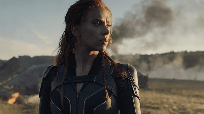 Natasha Romanoff in an empty field, with rising smoke behind her, in Black Widow (2021)