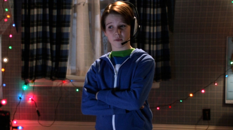 Finn standing next to Christmas lights in his bedroom while wearing a headset