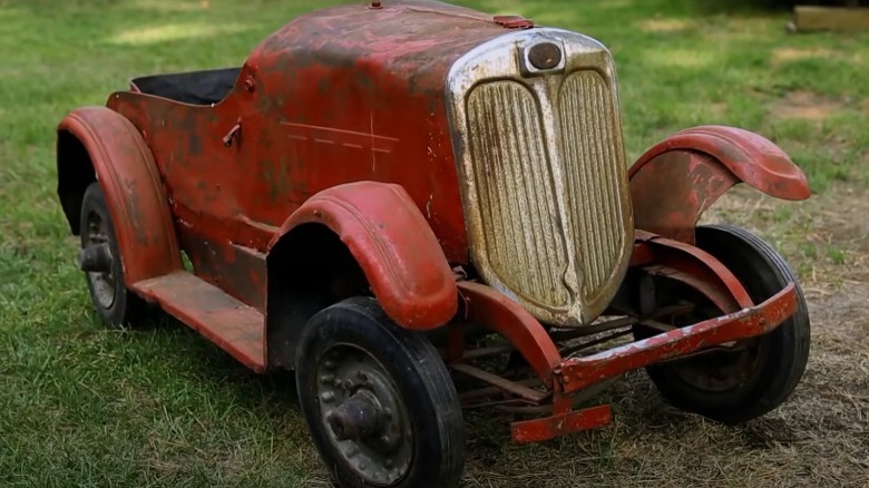 An antique pedal car outside