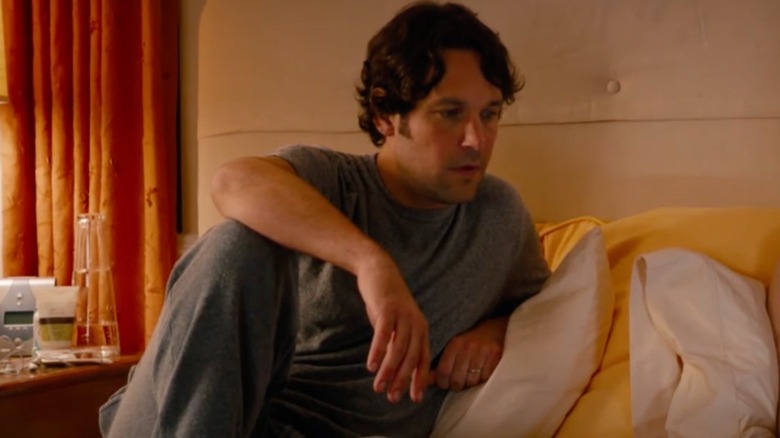 Paul Rudd sits on the bed