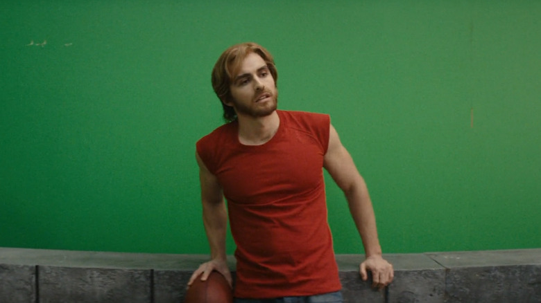 Dave Franco in a red T-shirt on a green screen set