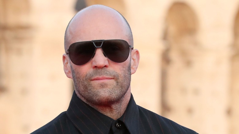 Jason Statham wearing black shirt and sunglasses