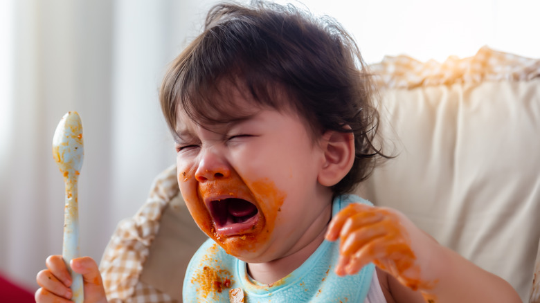 A crying baby with food smeared on face