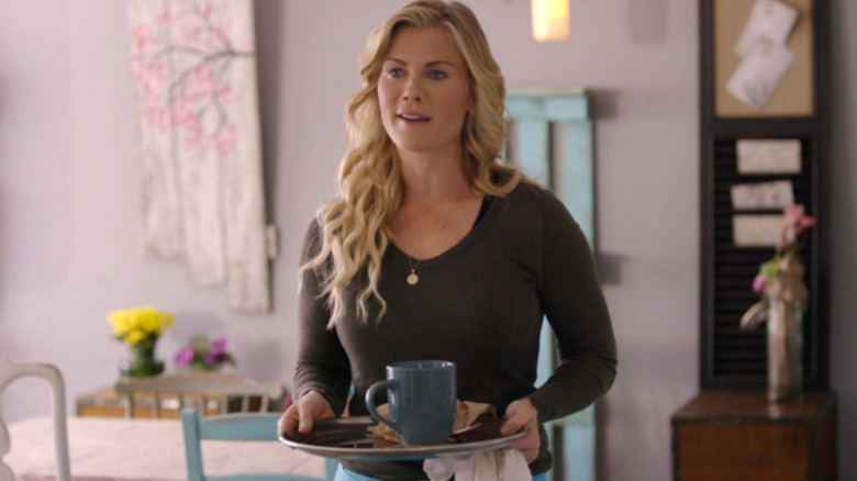 Hannah is standing in her bakery and hold a blue plate with a blue cup on top