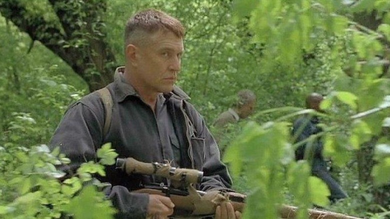 Thomas Beckett with his sniper rifle in the woods