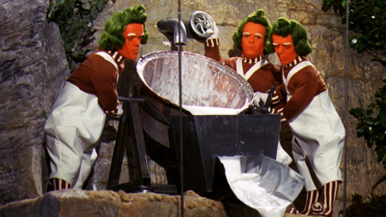 three Oompa Loompas pour milk from a large bowl