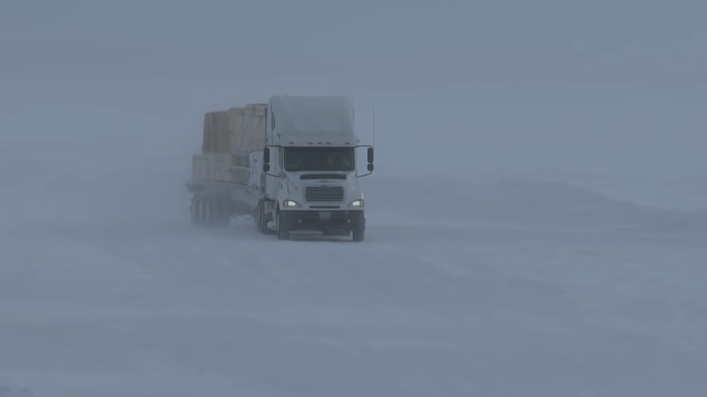 A truck passing through a snowstorm while out on the ice