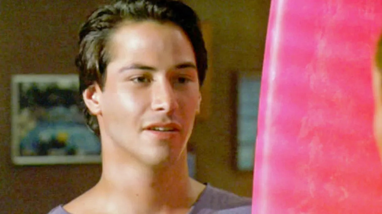 Reeves standing next to pink surfboard