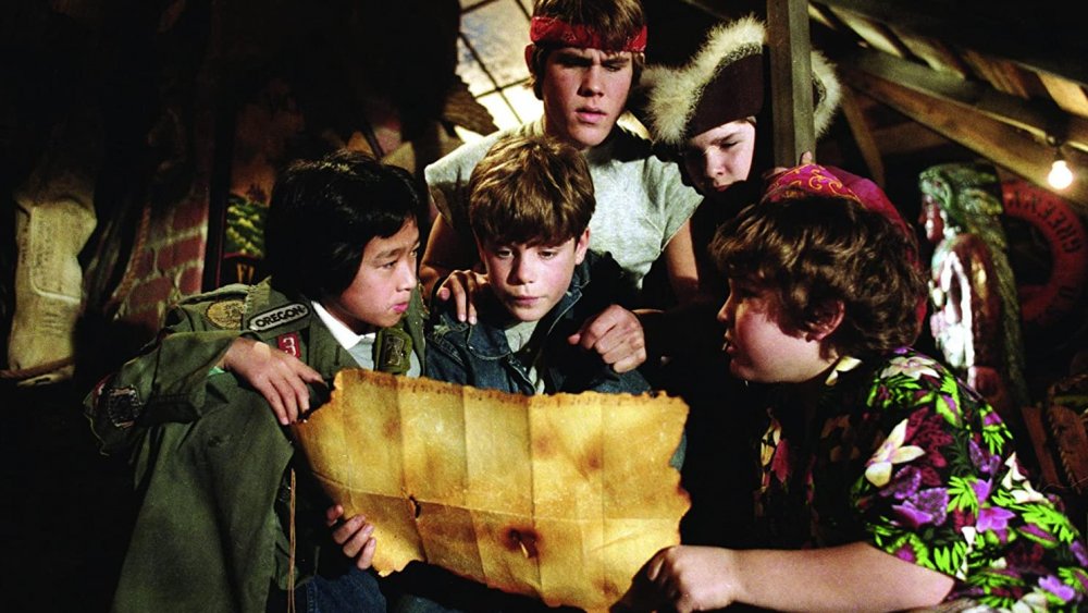 Boys cluster around a yellow treasure map in The Goonies