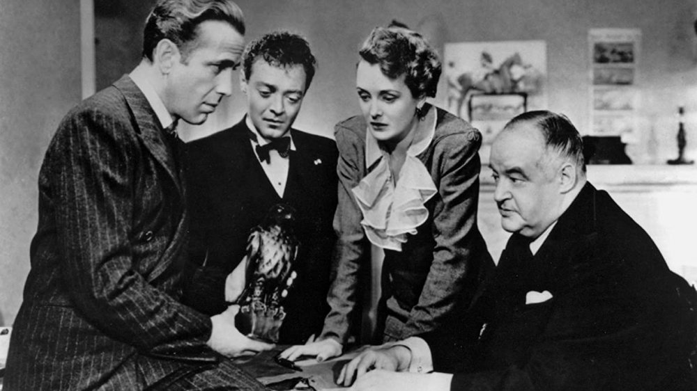 Four characters examine the bird statue in The Maltese Falcon