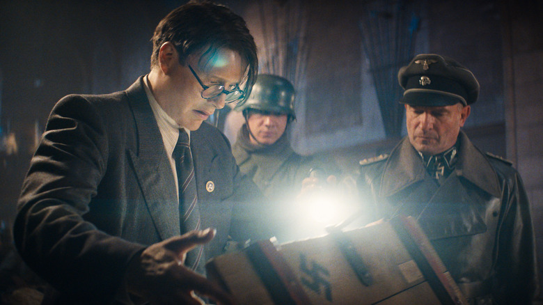 Jurgen Voller examines the contents of a box with two Nazi soldiers