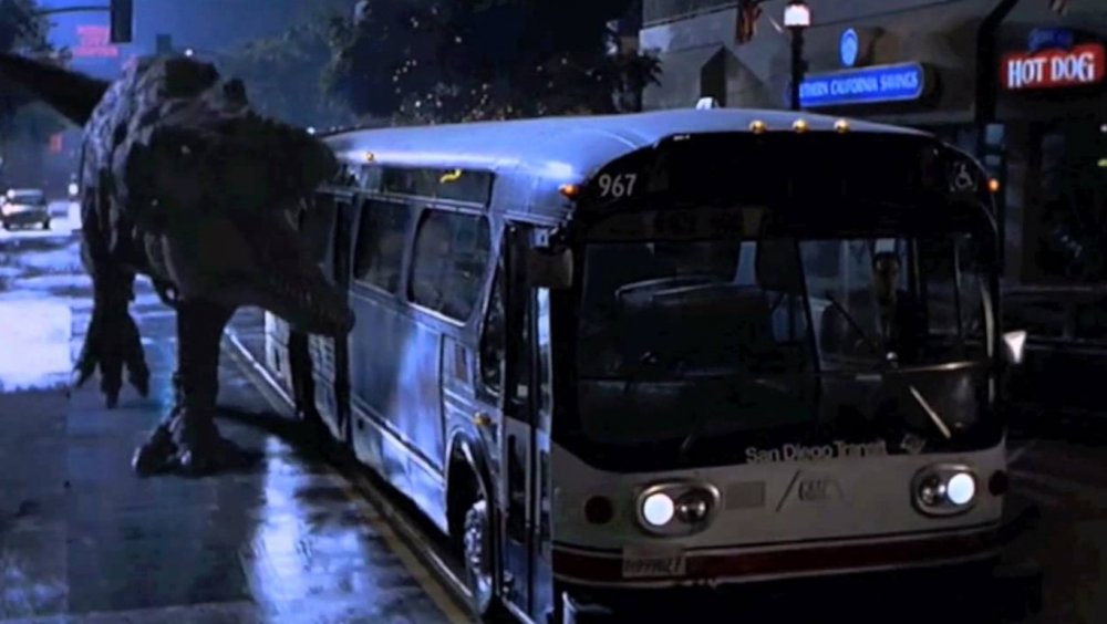 A Tyrannosaurus Rex runs alongside a city bus during Jurassic Park 2