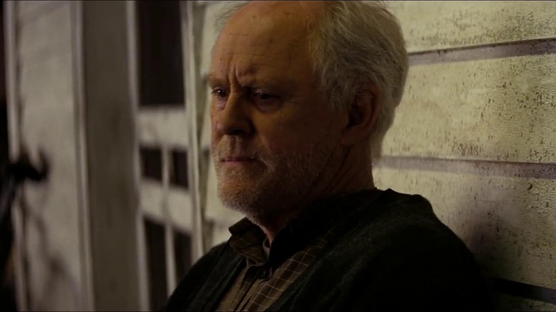 John Lithgow sitting and furrowing his brow