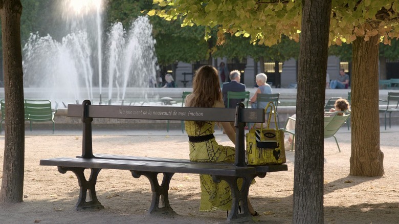 Emily Cooper sitting on a bench at the Palais-Royal garden