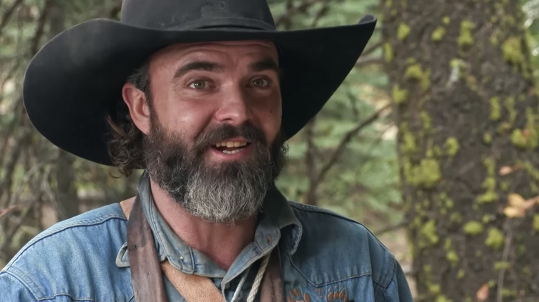 A bear hunter speaking to the camera in a log cabin