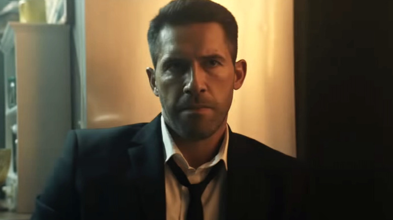 Scott Adkins scowling and wearing suit