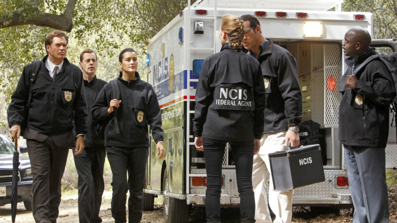 ncis agents standing around an open ambulance