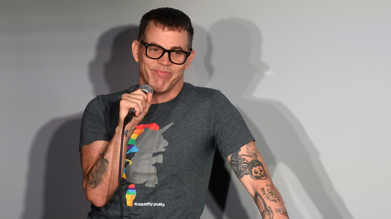 Steve-O smirks and holds microphone