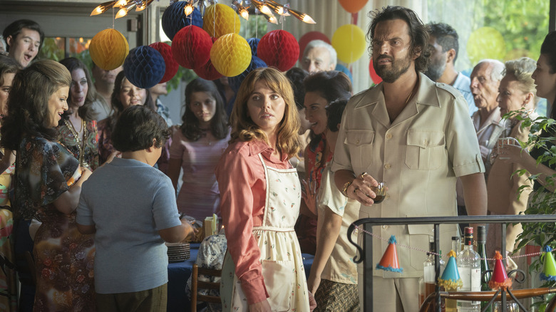 Ophelia Lovibond and Jake Johnson looking confused at a party surrounded by people