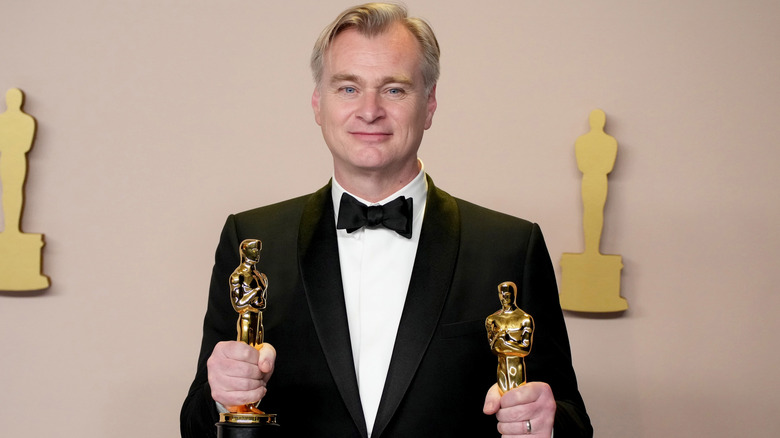 Christopher Nolan holding two Oscars