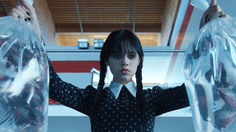 Jenna Ortega as Wednesday Addams holding two bags of fish