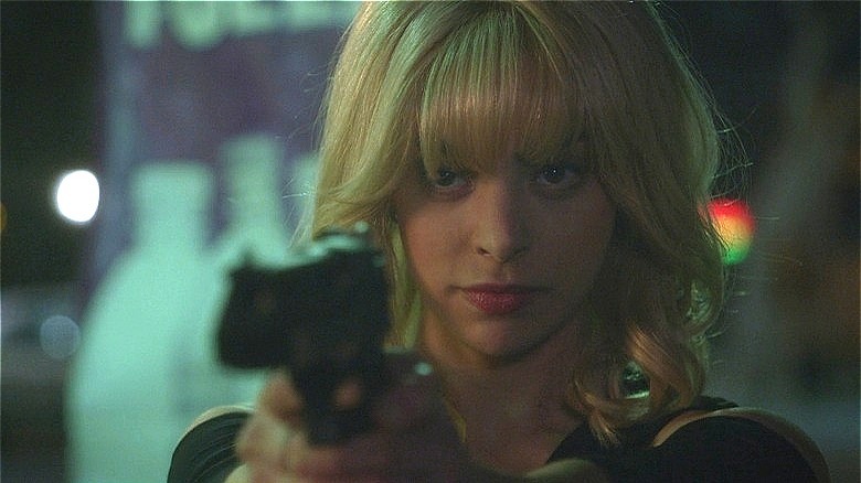 Gia Mantegna with blond hair aiming gun