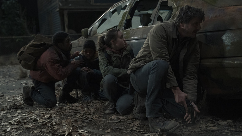 Four people hide behind a car