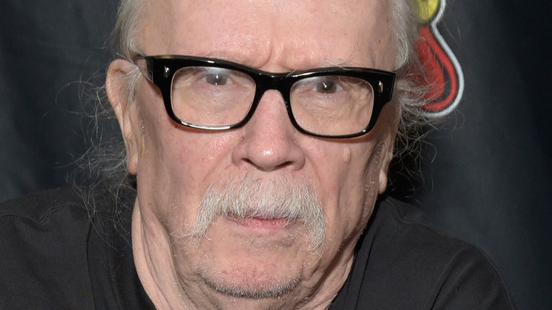 John Carpenter wearing glasses and looking into camera 