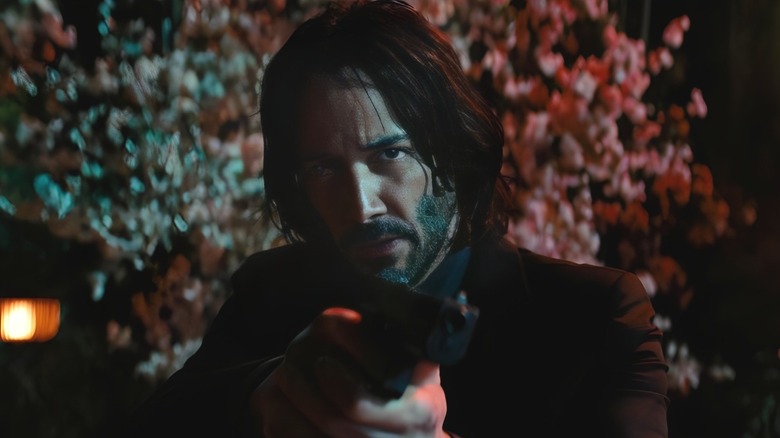 John Wick standing in front of cherry blossom trees