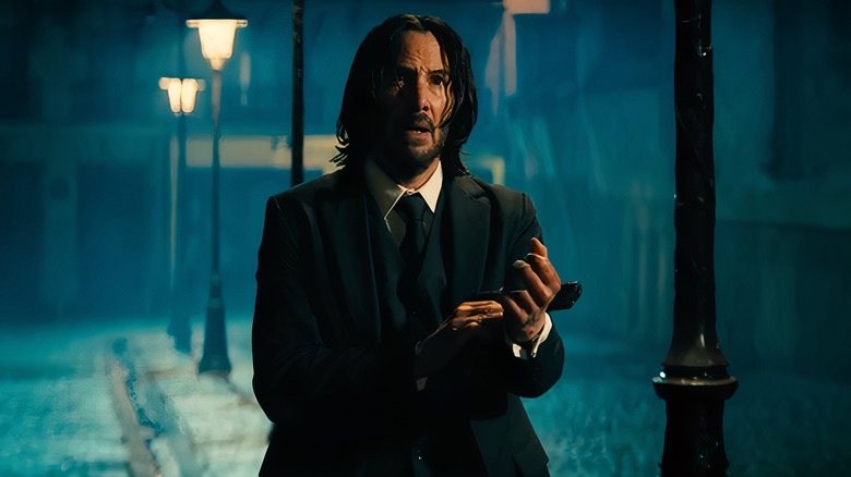 John Wick holding pistol next to street lamp