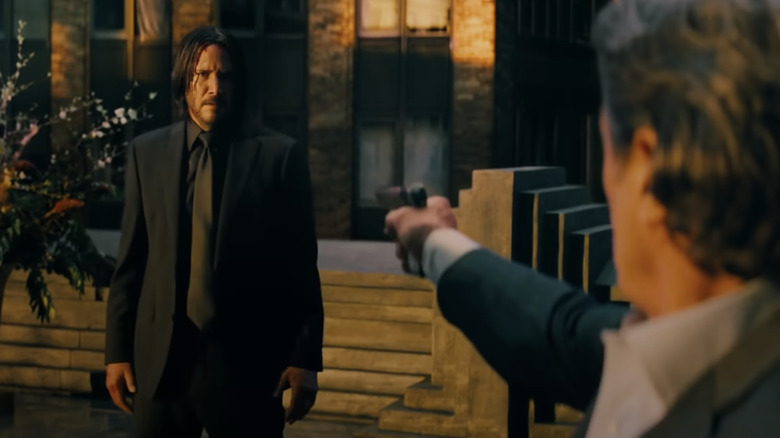 Winston aims his gun at John Wick