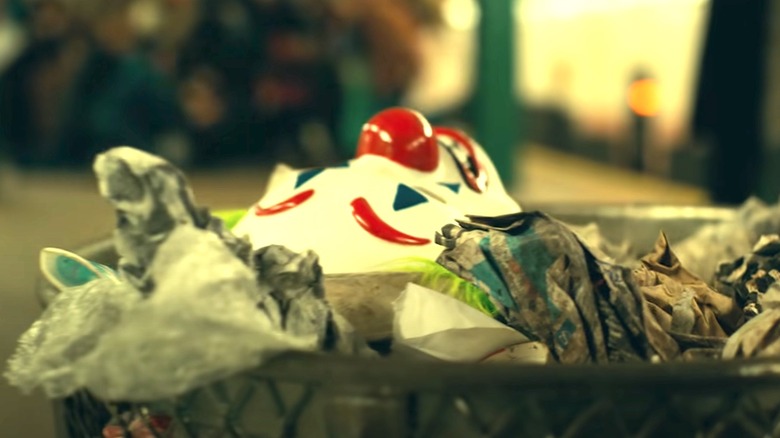 Joker mask laying in trash 