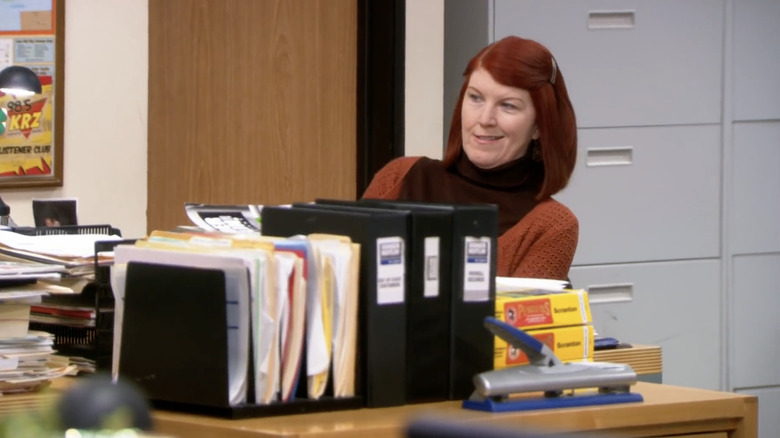 Meredith Plamer sitting at desk wearing orange