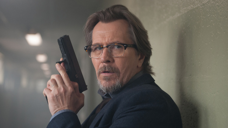 Gary Oldman holds a gun