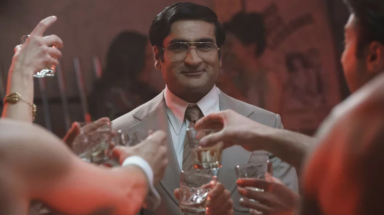 Kumail Nanjiani as Steve Banerjee toasting with glasses