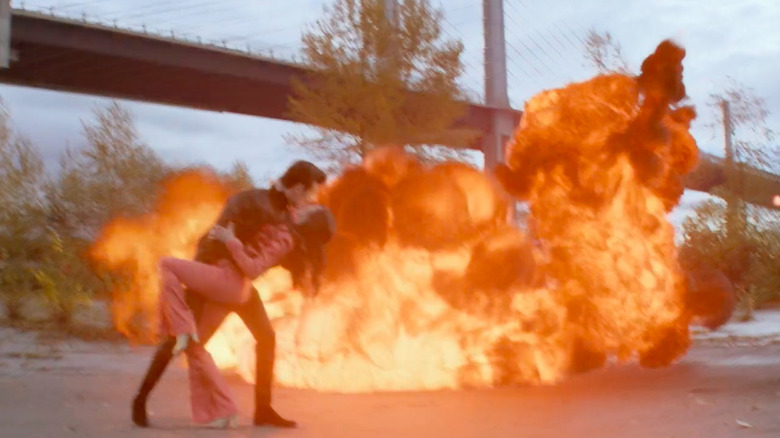 Dennis kissing Althea in front of an explosion