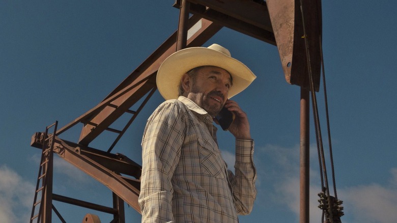 Tommy Harris speaking on the phone in front of an oil rig