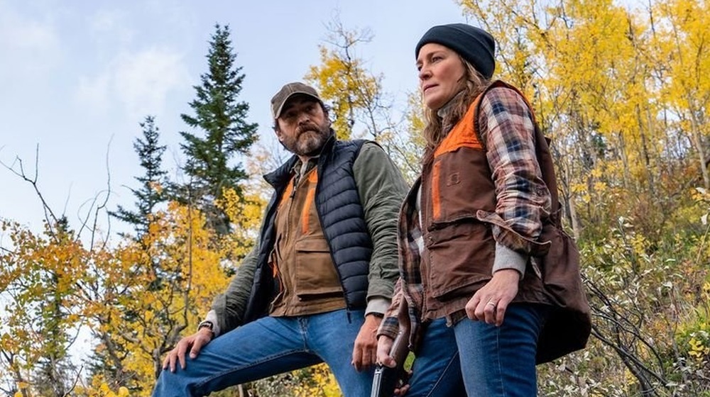 Demian Bichir and Robin Wright stand on a hillside in the woods