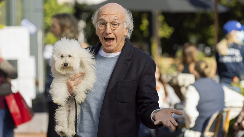 Larry David smiling and holding dog