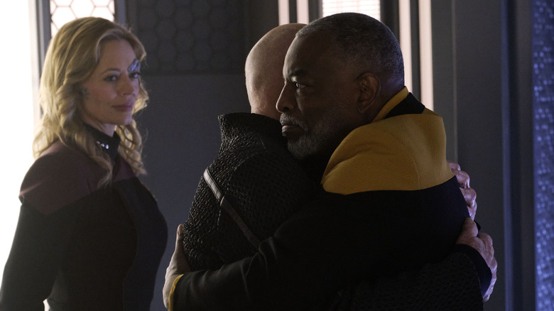 Geordi La Forge and Jean-Luc Picard embrace while Seven of Nine looks on