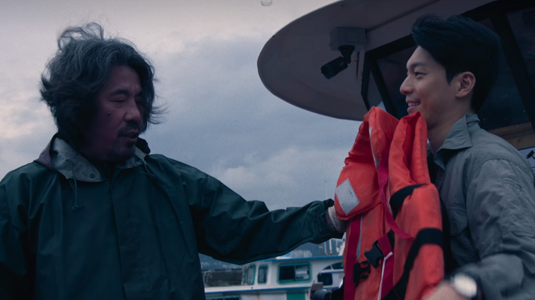 Captain Park pushes a life jacket onto Hwang Jun-ho in "Squid Game" (2024)