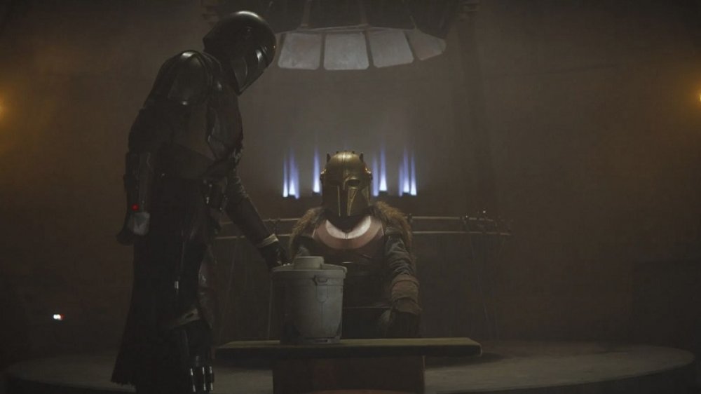 Pedro Pascal as Din Djarin and the Armorer look at the camtono in The Mandalorian