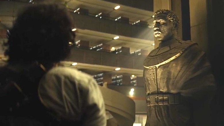 Loki looking at Kang statue