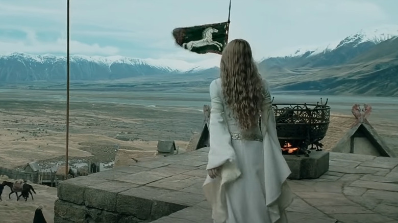 Eowyn standing by a flag looking at the landscape