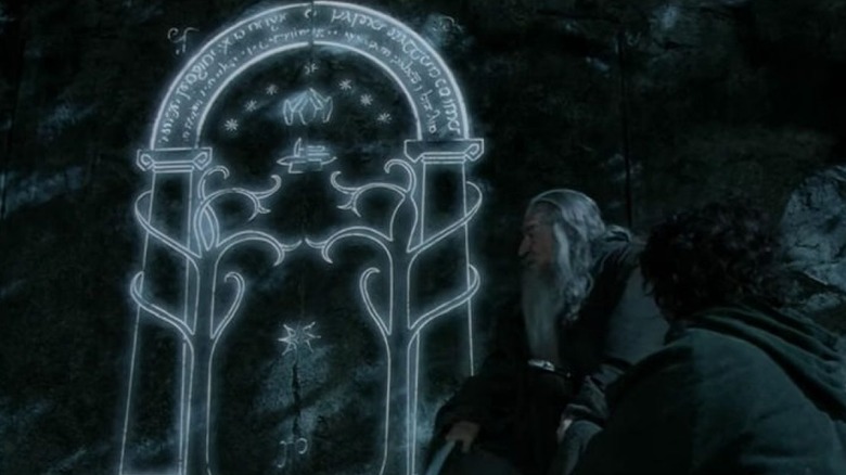 Gandalf and Frodo sit in front of the Doors of Durin